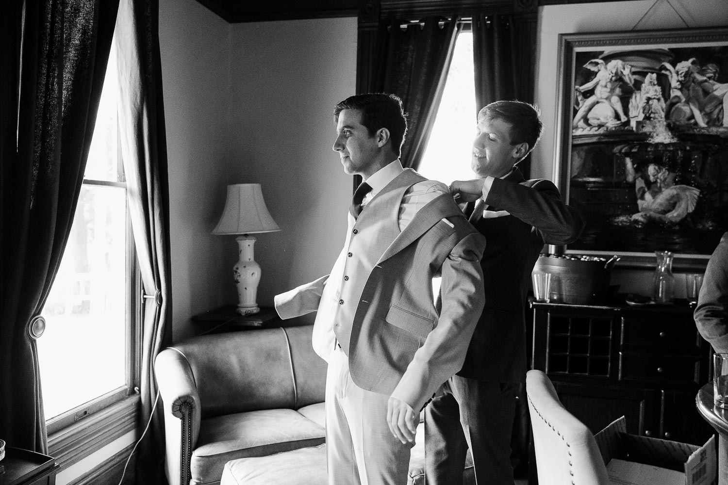 The groom is assisted with his wedding jacket at the cottage at Barr Mansion, Texas