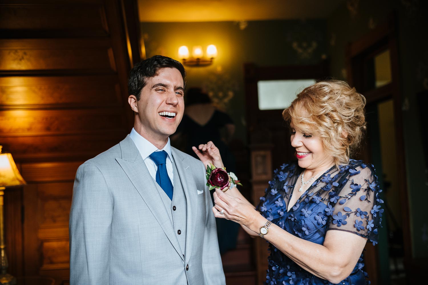 At Barr Mansion, Texas the mother of the bride pins a flower to the grooms jacket