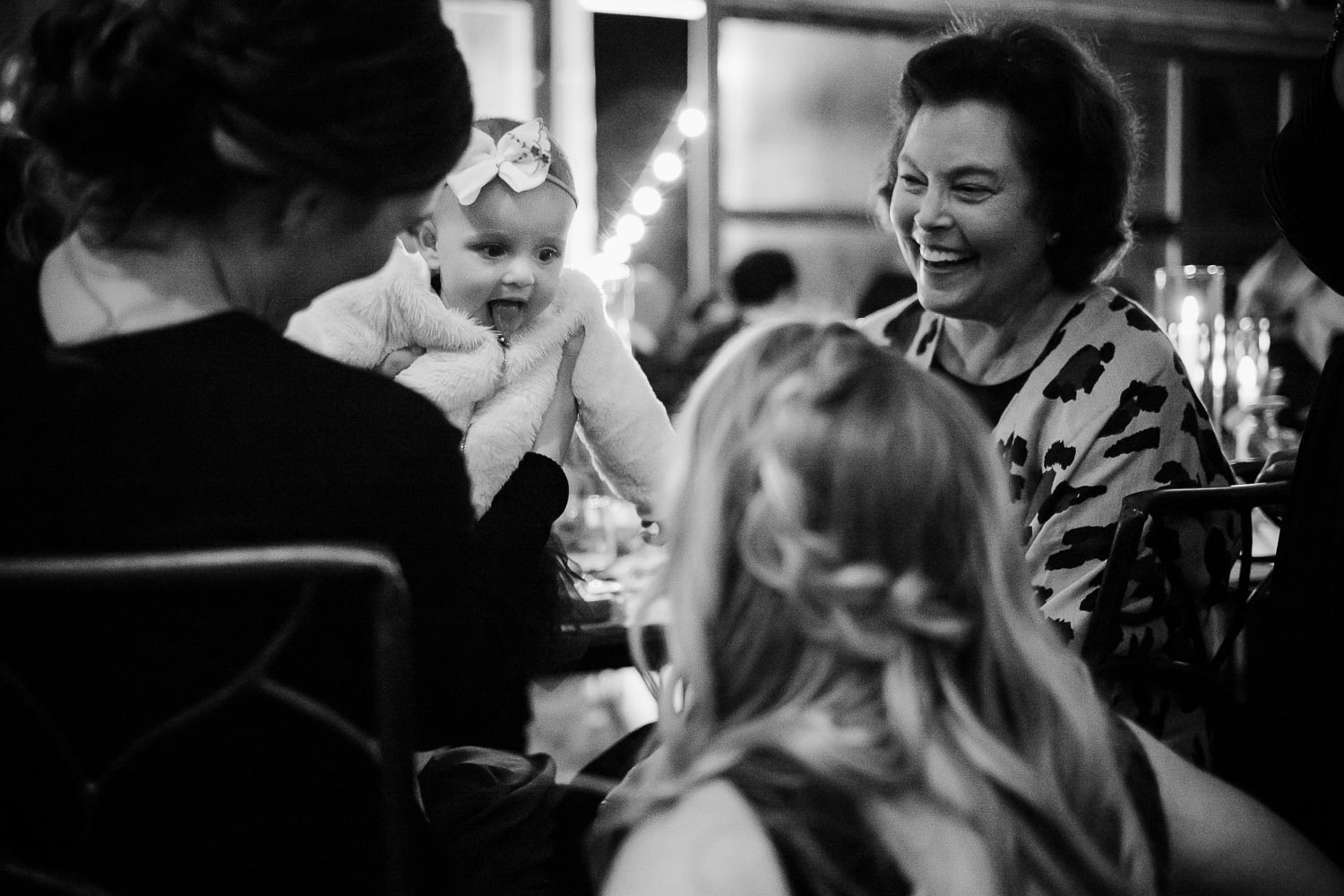 A candid shot of a baby girl sticking her tongue out at a young guest in a humorous moment moment