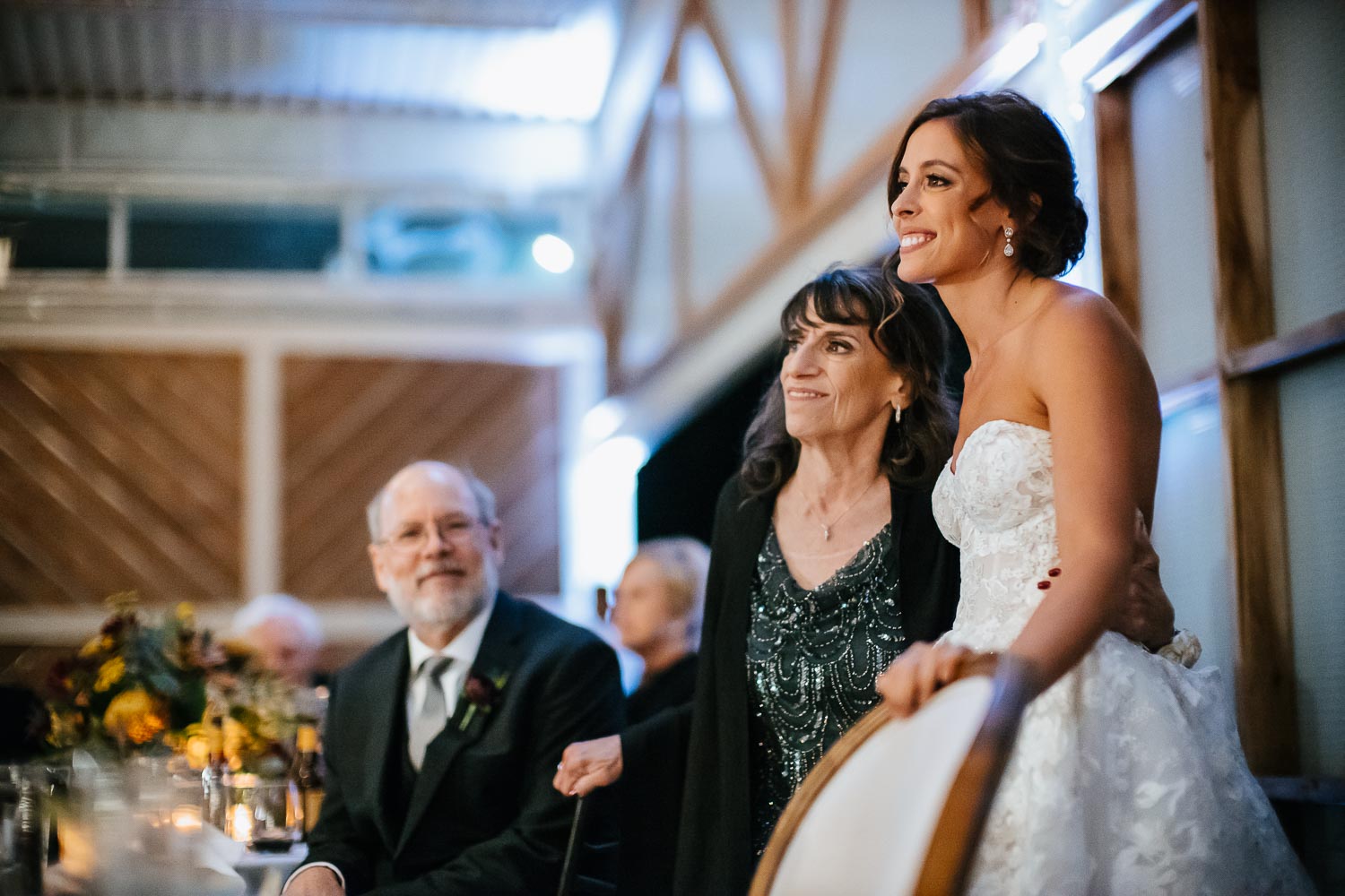 Mother of the bride and bride watch first dance with groom and his mother
