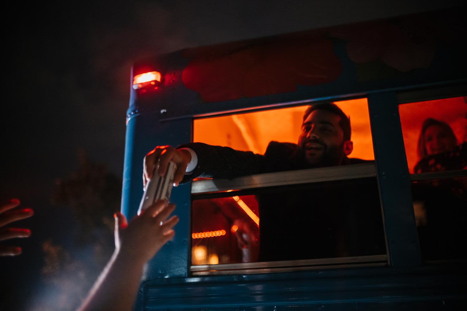 Guest passes beer to an outreached hand on bus heading toward after party, in Austin Texas