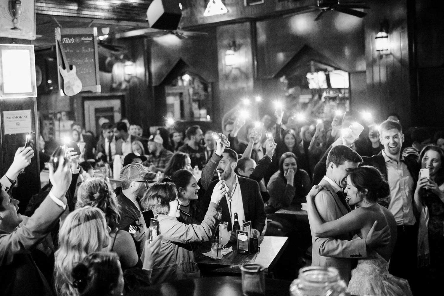 At Darwin's Piano Bar in downtown Austin, couple dance with guests raising their phones lighting the couple