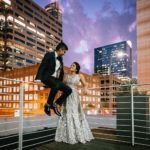Newlywed couple Neha and Mrugesg pose on top of Brazos Hall with night time view of downtown Austin Brazos-Hall-South-Asian-Indian-wedding-_-Neha-Mrugesh-Philip-Thomas-Photography-1