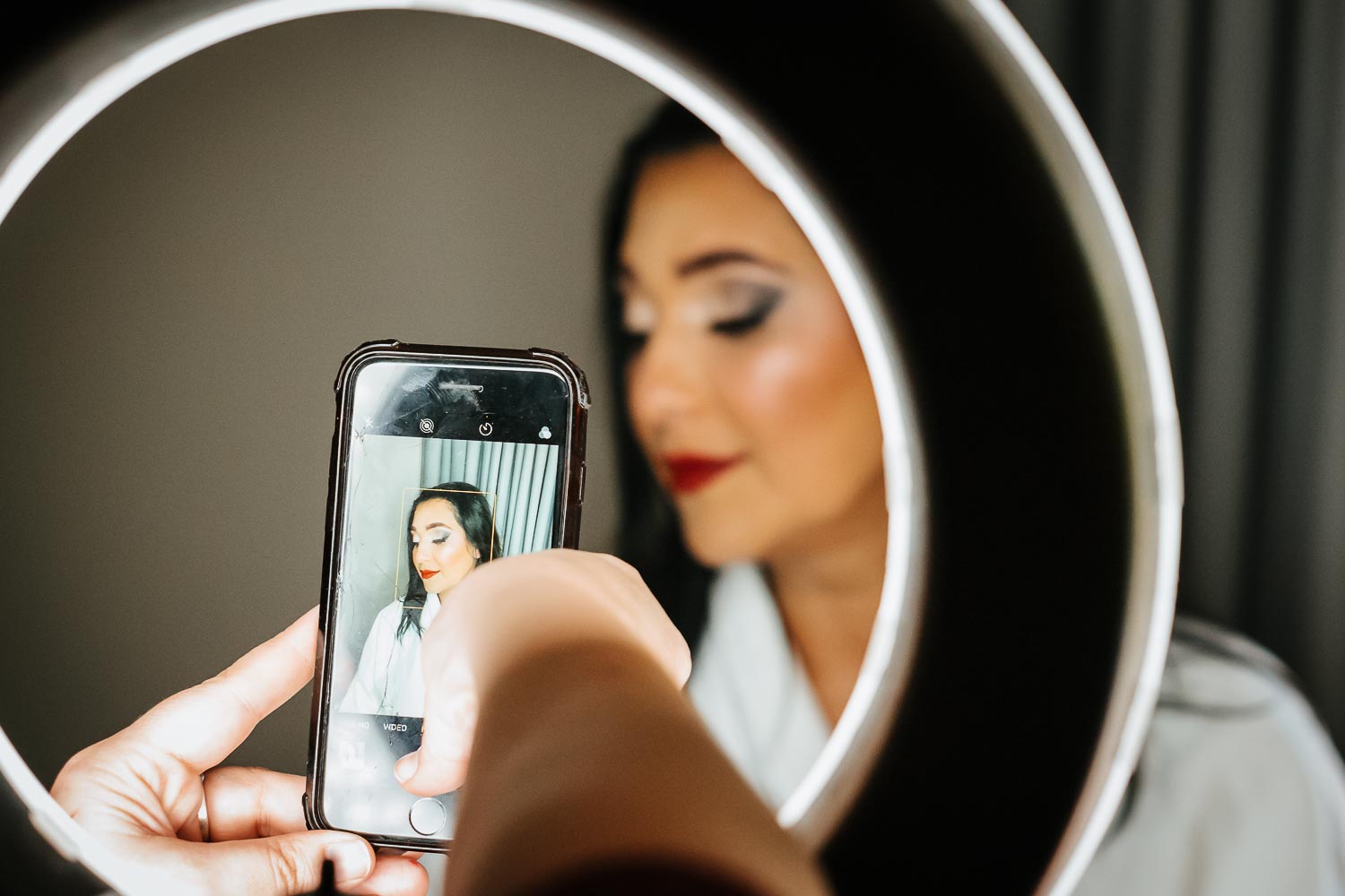Hair stylist takes a photo of the bride with her phone