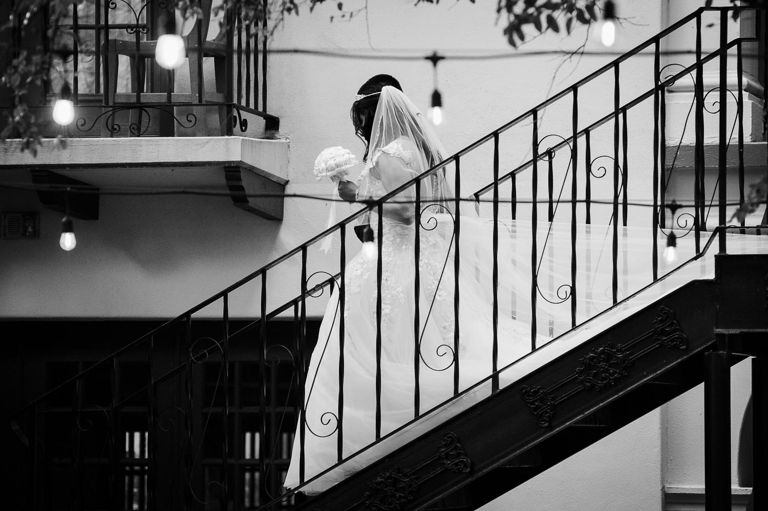 The wedding commences with the bride coming down courtyard staircase at Omni La Mansion Riverwalk hotel in San Antonio Texas