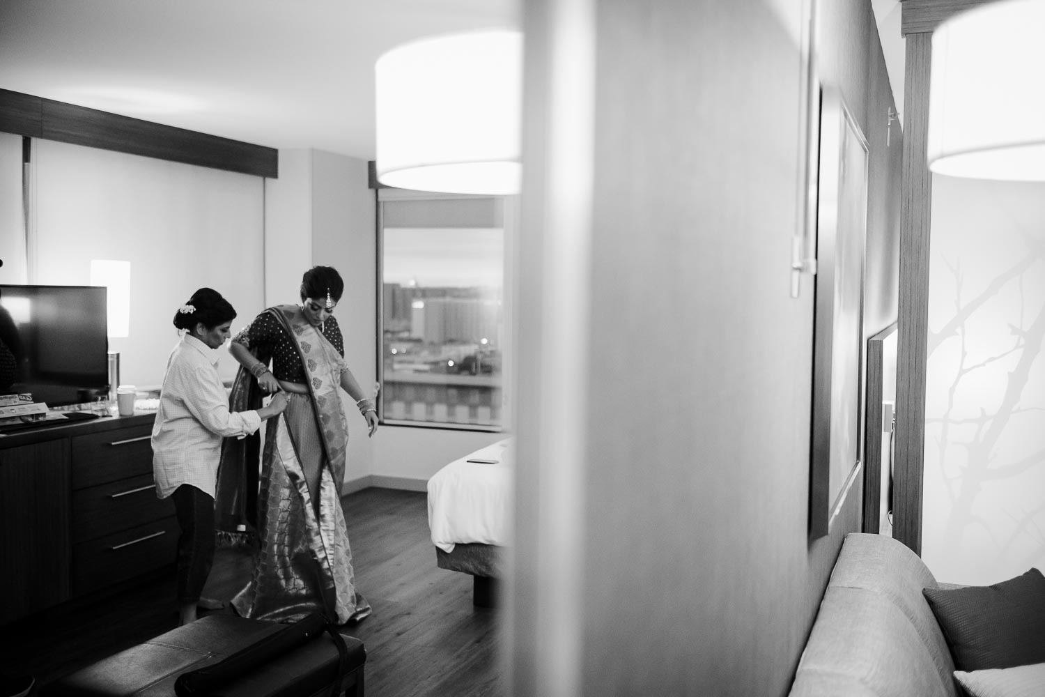 The bride and mother help get drssed in a reflection of a mirror at at Hyatt Place Austin