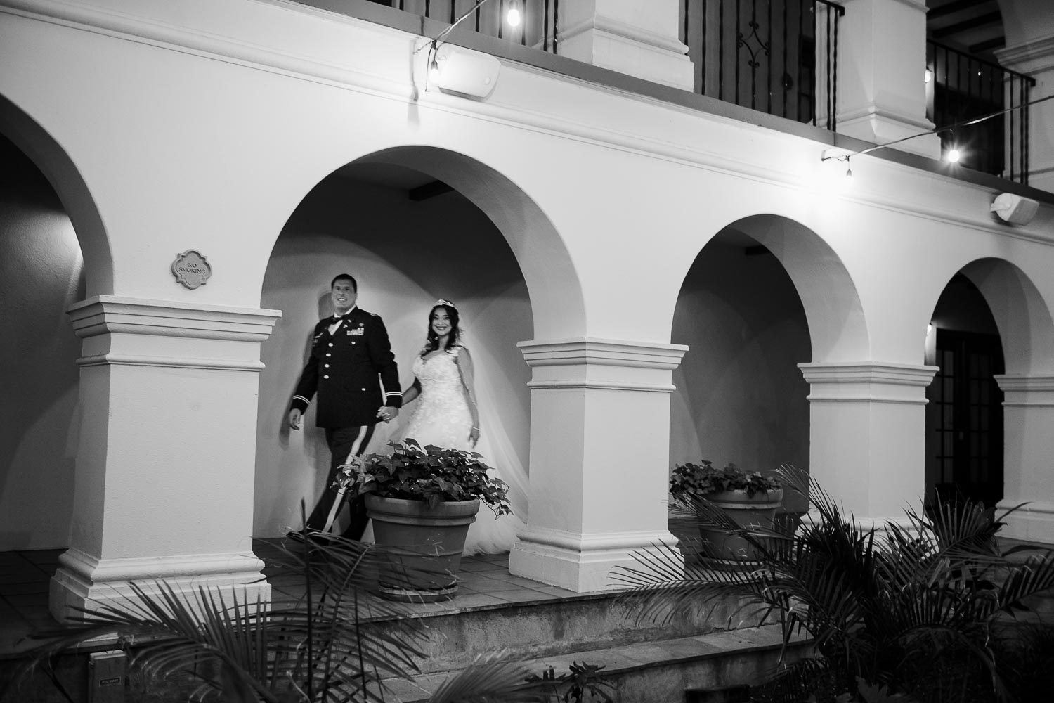 The couple stride through the arches at Omni La Mansion Riverwalk hotel in San Antonio Texas on their wedding day