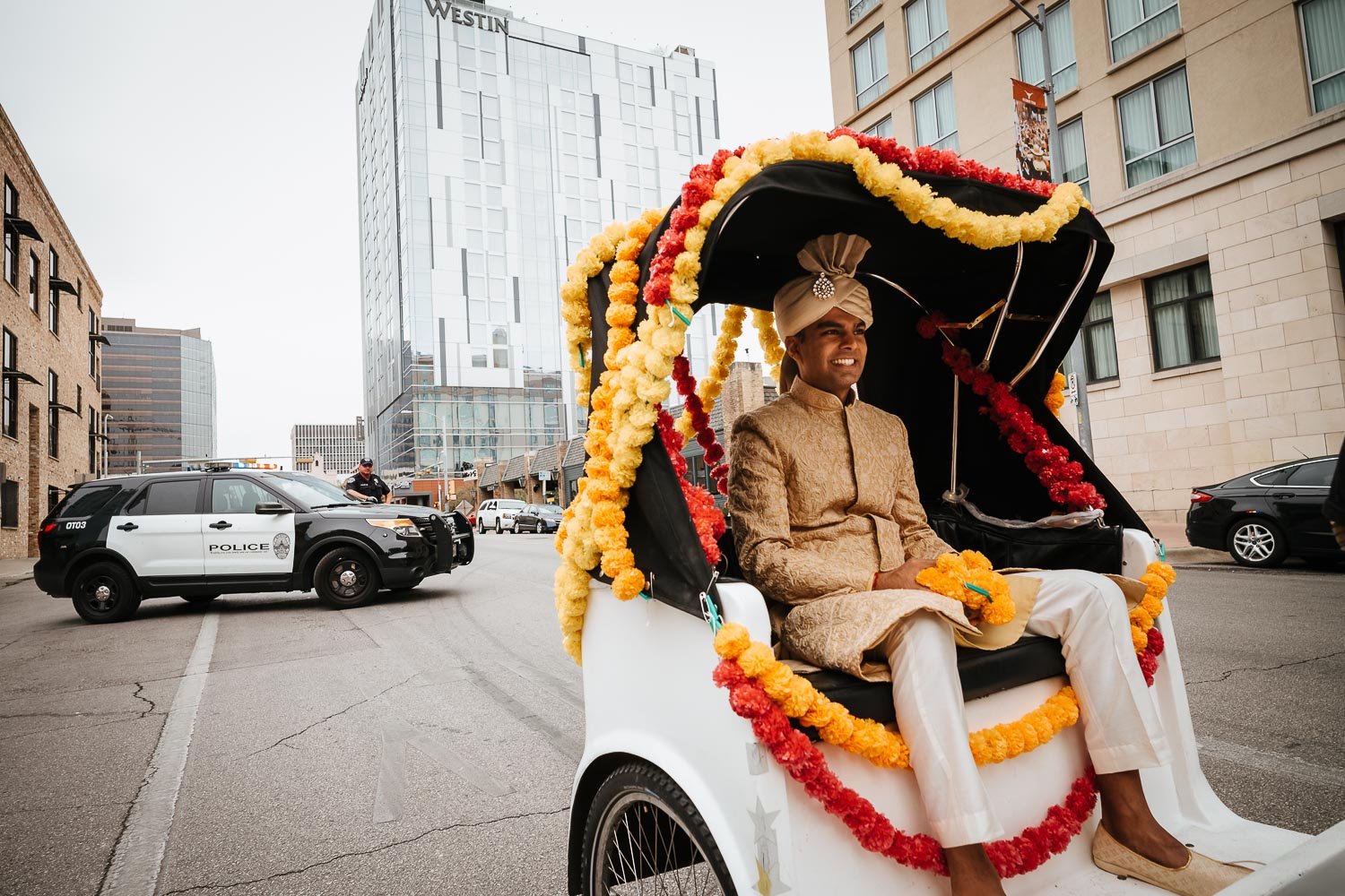 The groom in a pedicab Brazos Hall Austin South Hindu asian wedding ceremony during the Baraat ceremony