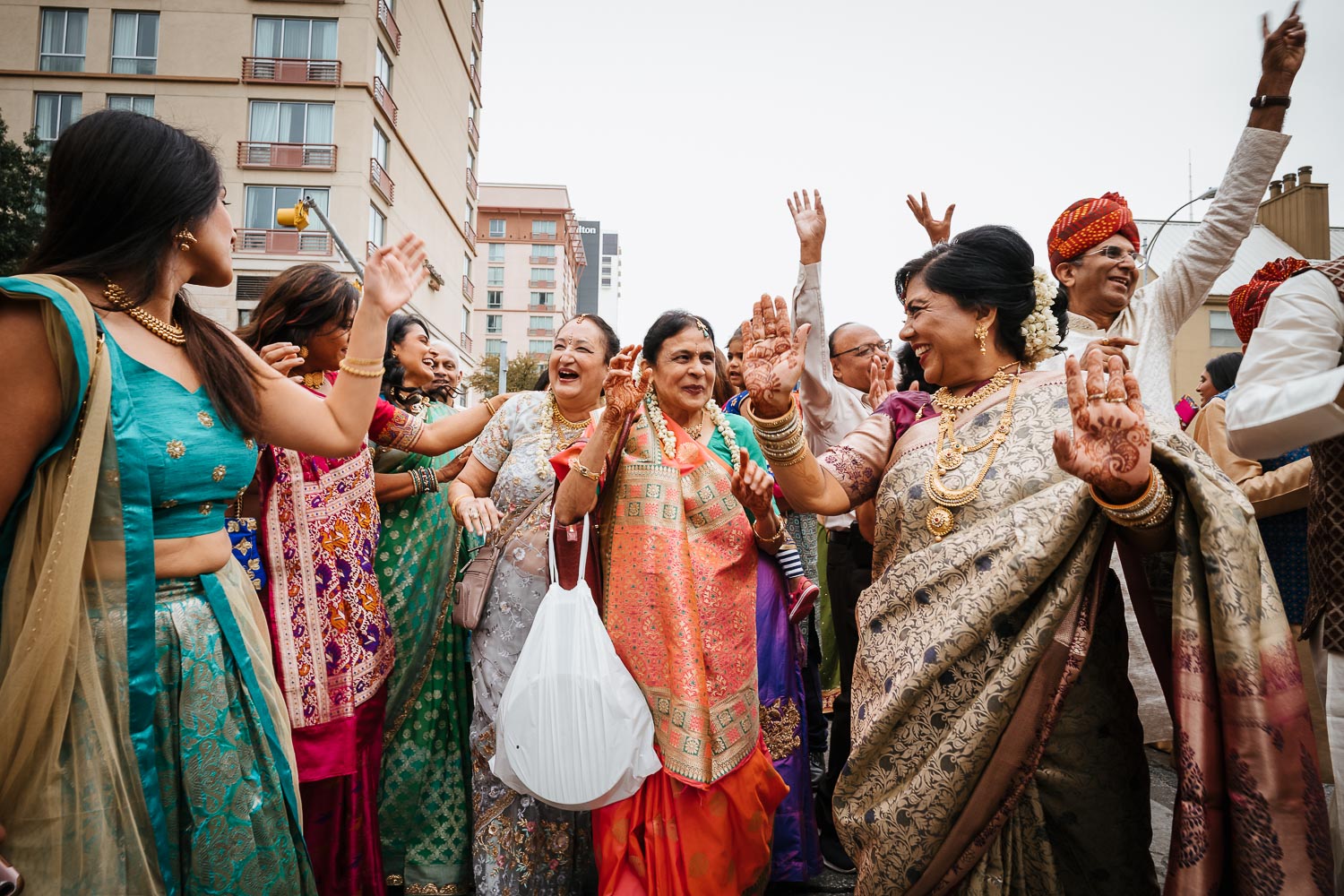 Female relatives dance in vibrant colorful saris during a Baraat at Brazos Hall Austin South Hindu asian wedding ceremony