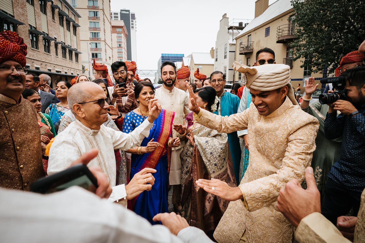 Father of the bride and groom dance together during the Baraat Brazos Hall Austin South Hindu asian wedding ceremony