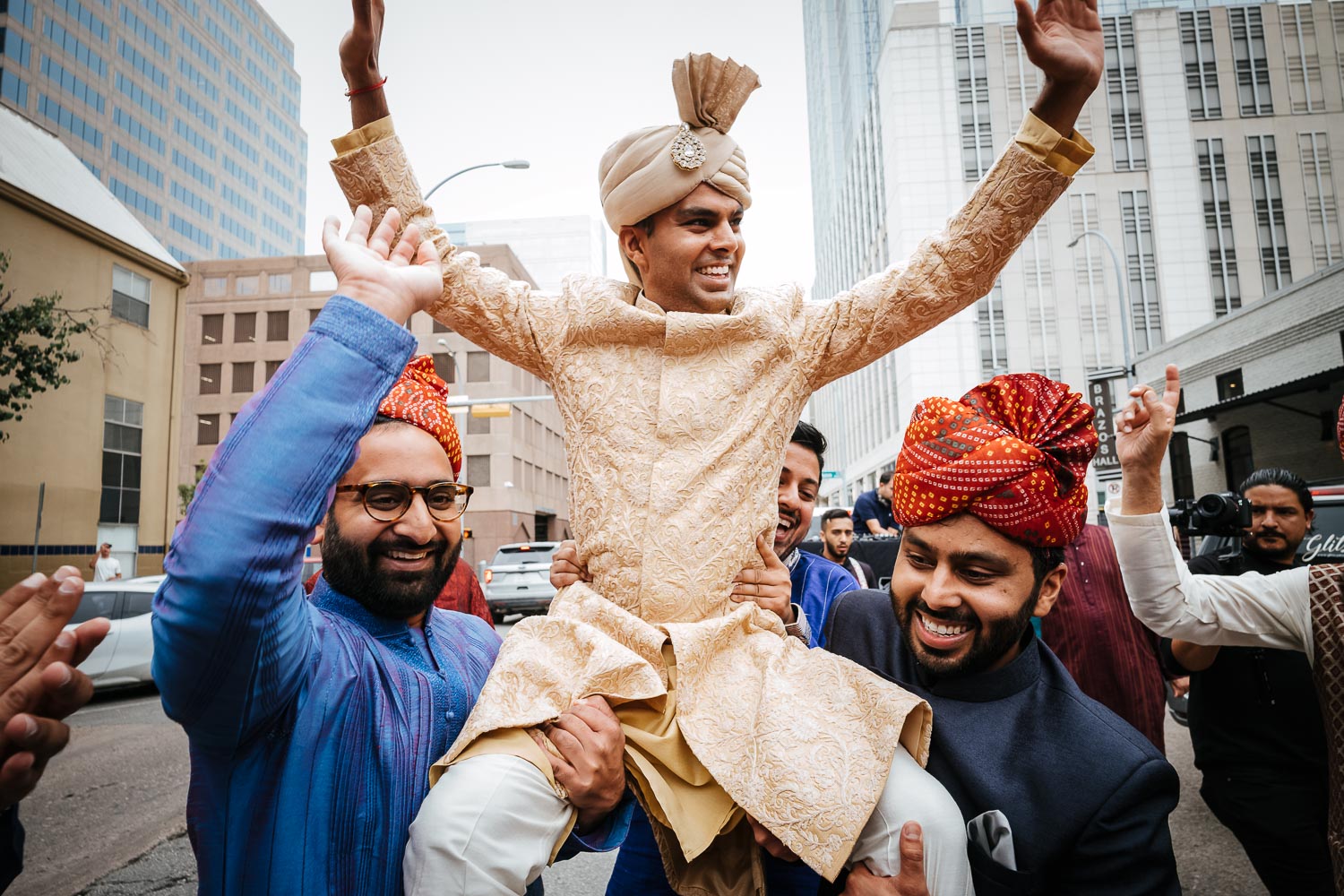 During a baraat, the groom is raised up on the shoulders of family friendsBrazos Hall Austin South Hindu asian wedding ceremony