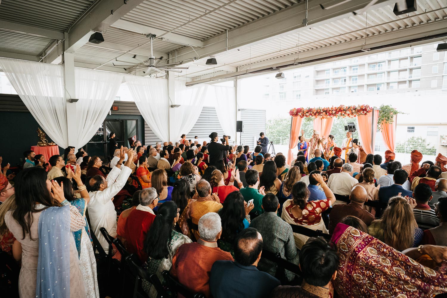 Brazos Hall in Austin Texa South Asian ceremony shows guests packed to view