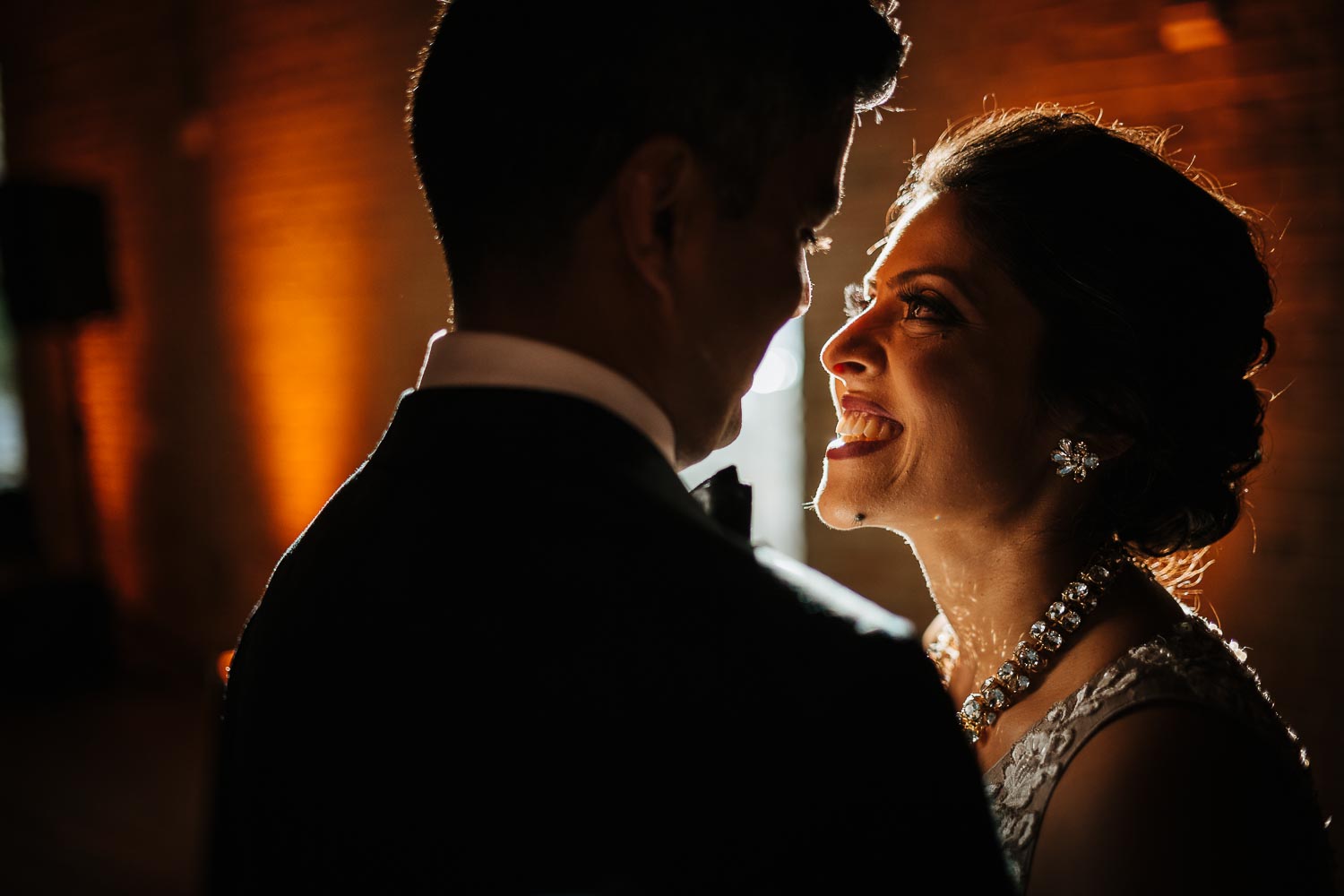 Backlight strikes brides face as she looks at the grroom at The groom leaves the wedding reception during the Vidai at Brazos Hall Austin