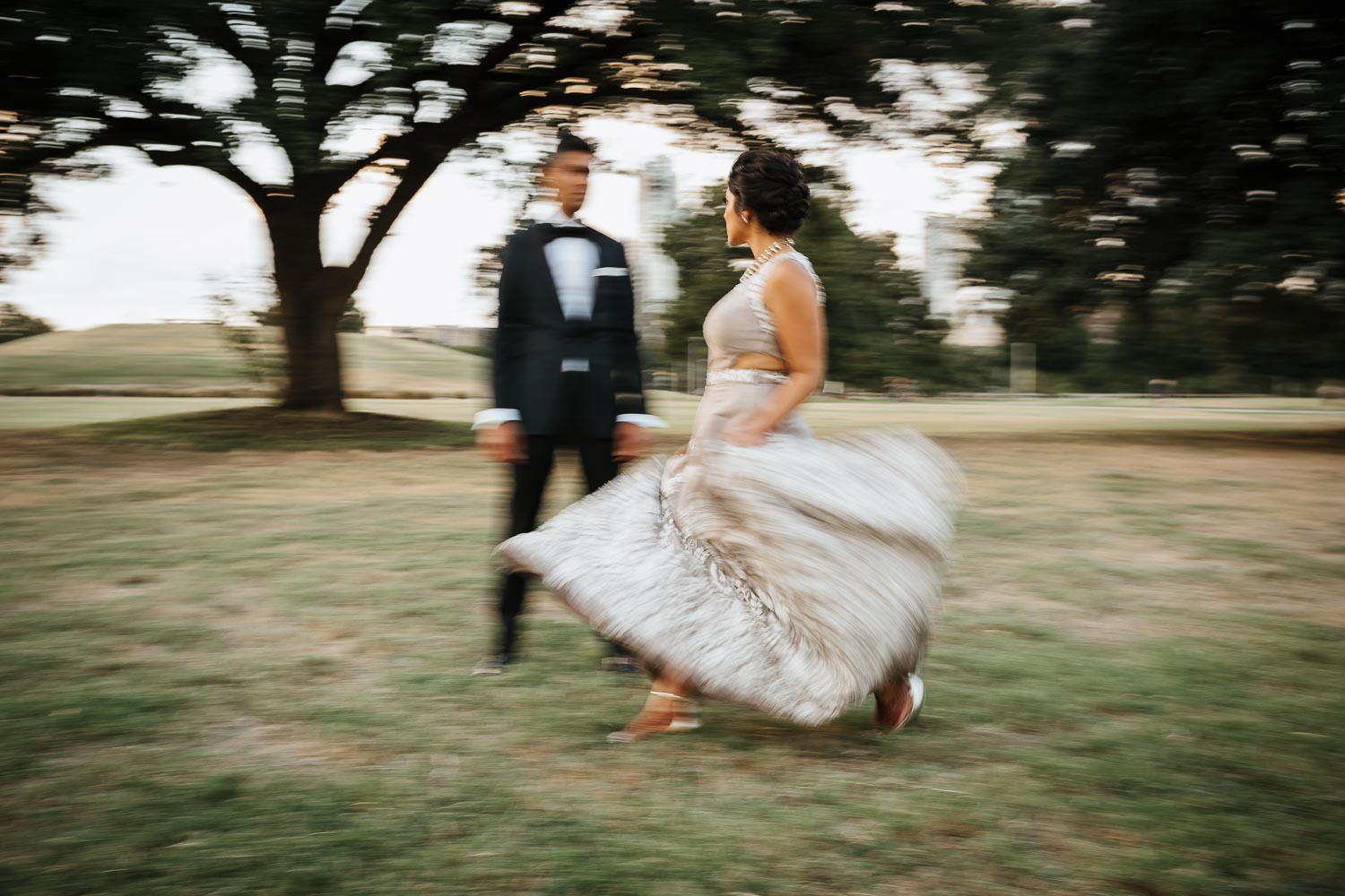 Slow dragged shutter with bride walking past groom at Butler Park Austin