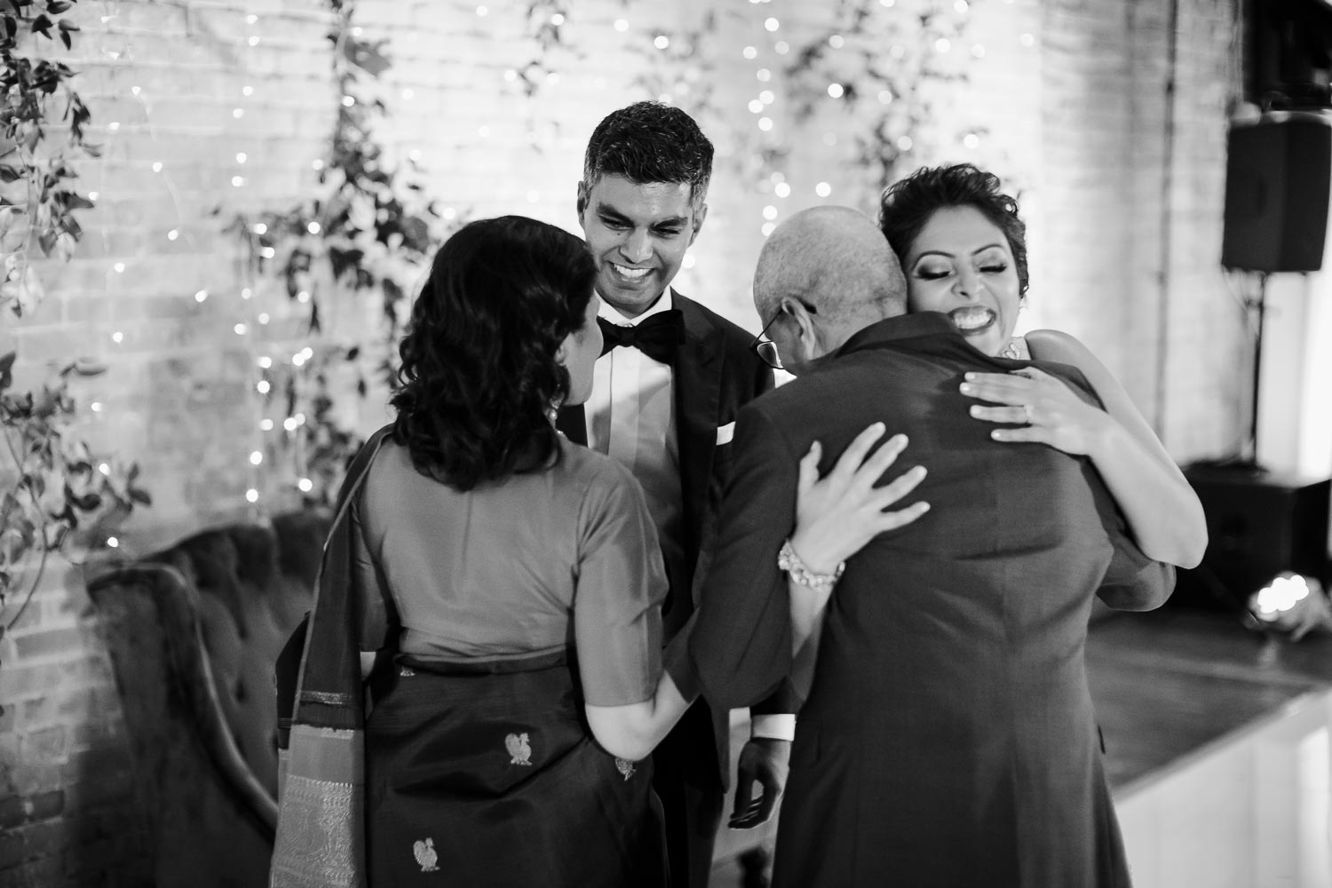 Brides parents hug couple at wedding reception