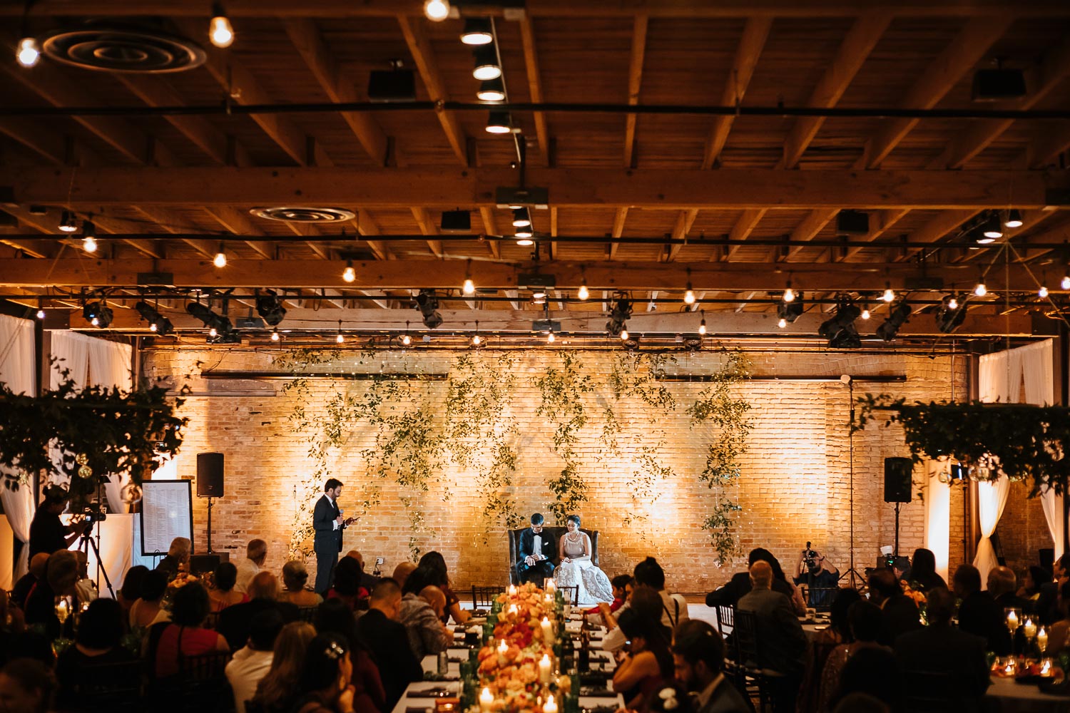 A wide angle of a wedding reception at Brazos Hall during speeches