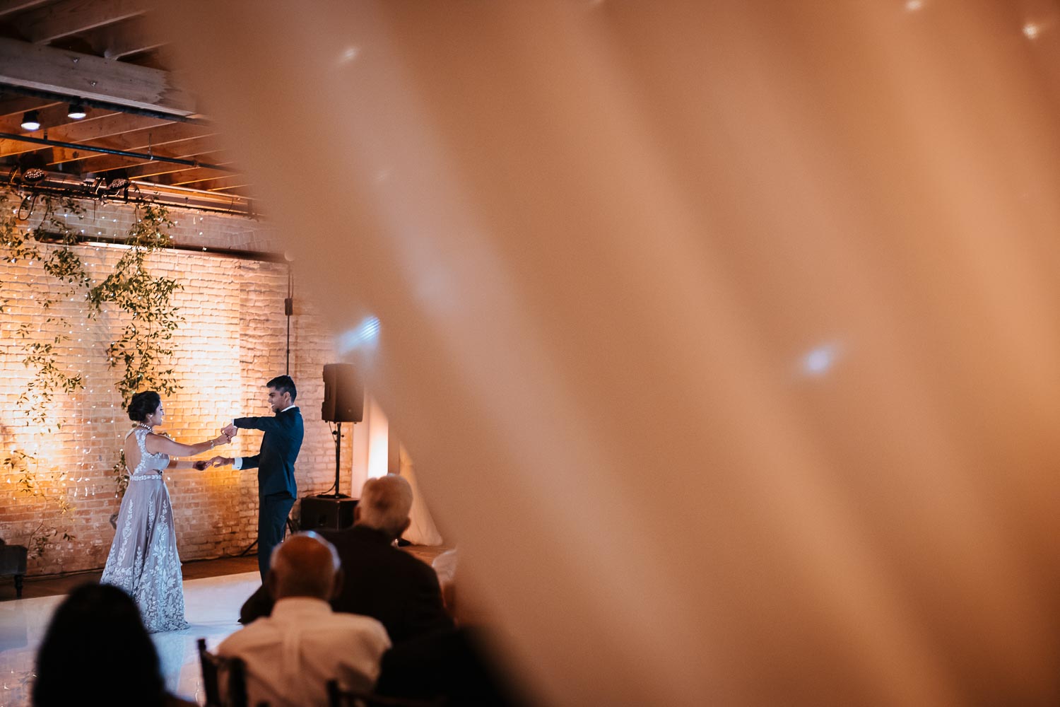 First dance fro married couple at wedding reception shot behind drapes