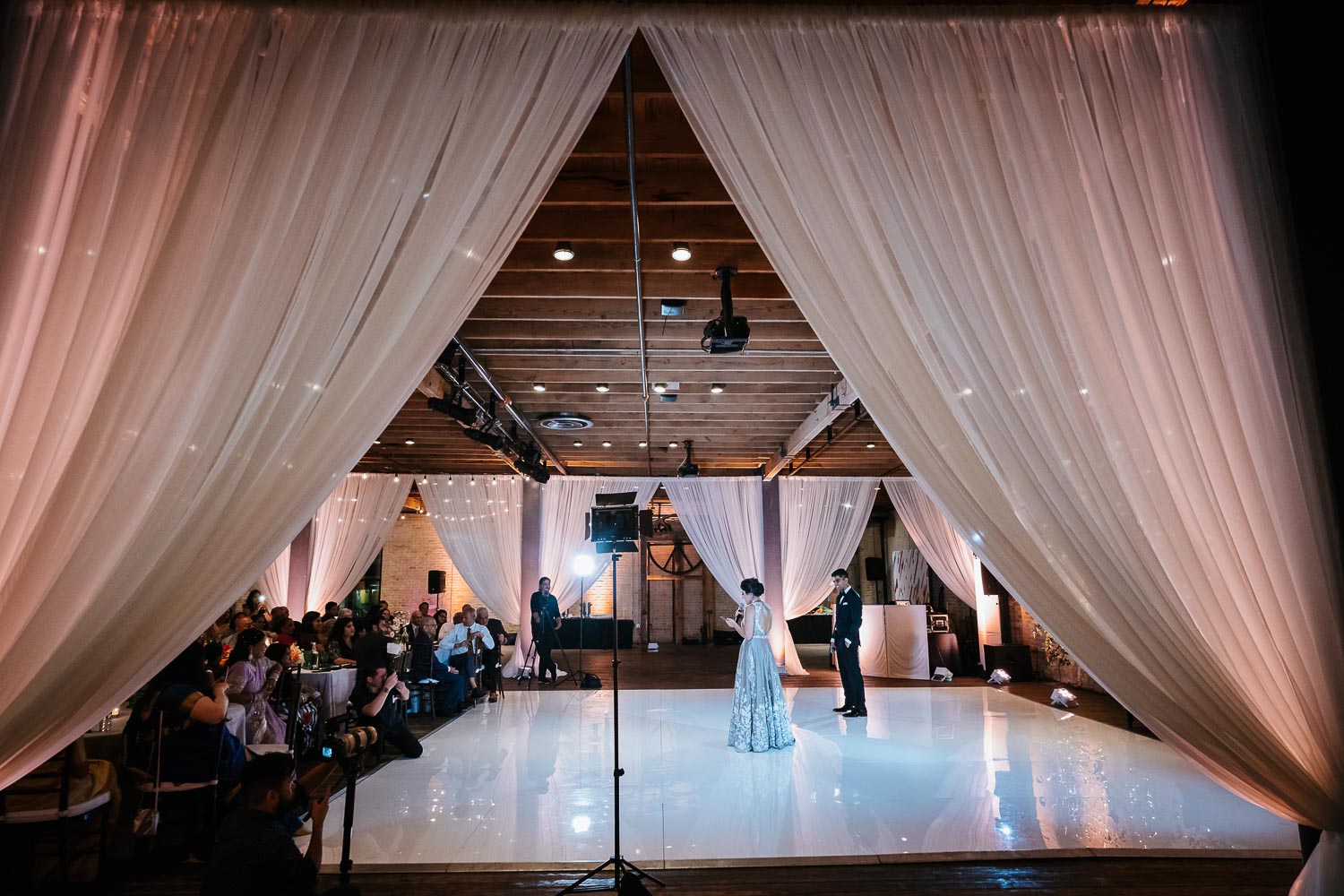 Wide angle showing drapes and decor during couples speech to guests at Brazos Hall