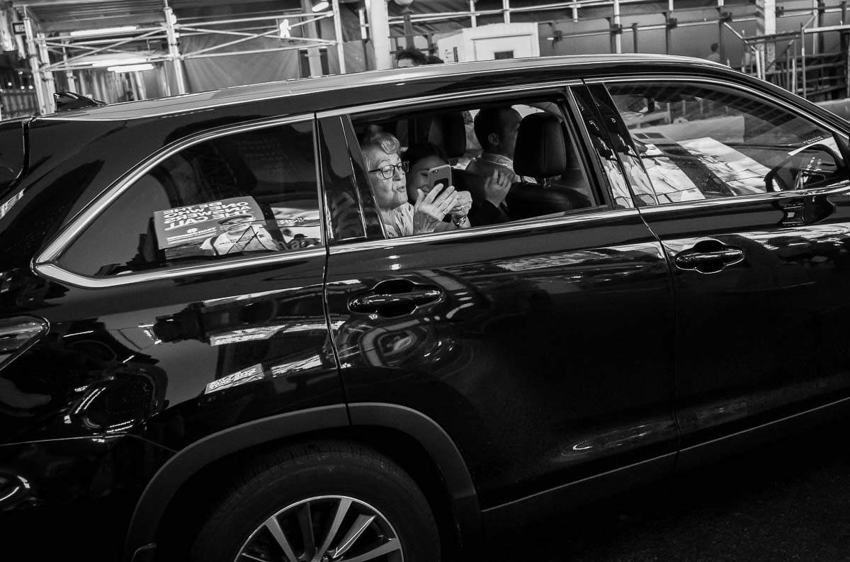 A tourist peaks out with her car in Time Square, NYC -street photography in New York by Philip Thomas - L1000197