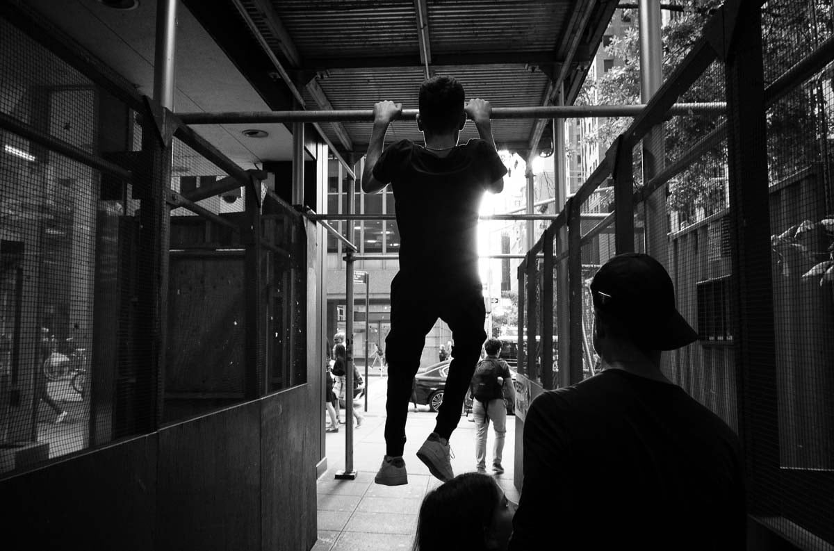 A young man jumps up on scaffolding on 46th street. Street photography in New York by Philip Thomas L1000266