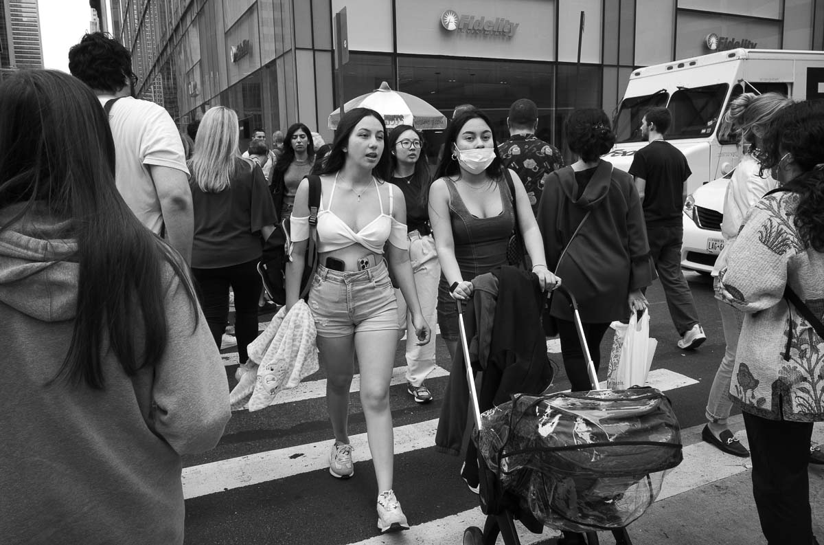 Phones slotted in the hips, two ladies cross a crosswalk in NYC - L1000627