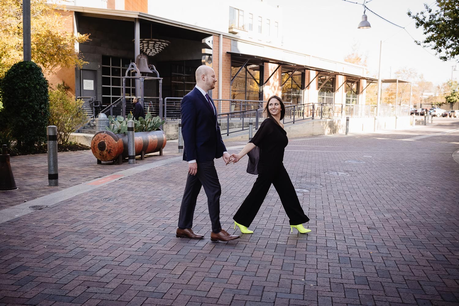 Couple cross pedestrianized street at the Pearl Market San Antonio engagement shoot