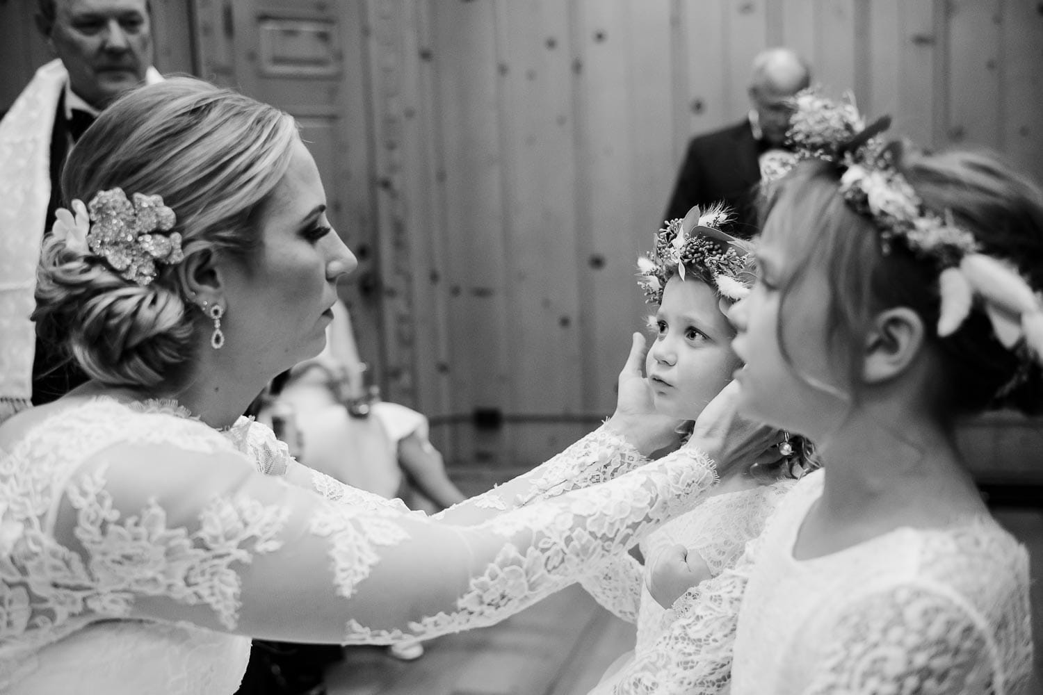 The bride fixes flowers on one of two flowergirls