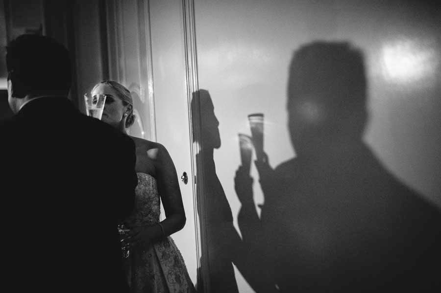 Shadow on wall shows clinking of glasses and the couples at The Houstonian during cake cutting - a WPJA award winning images