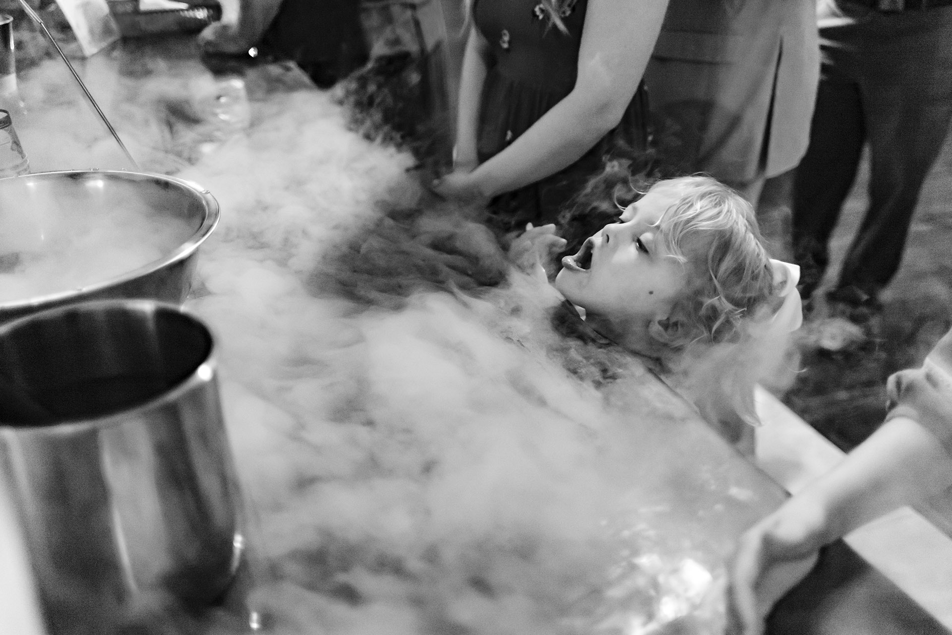 Little girl at wedding reception breathes smoked ice at a bar station at Bridal Oaks Weddings and Events Houston Texas