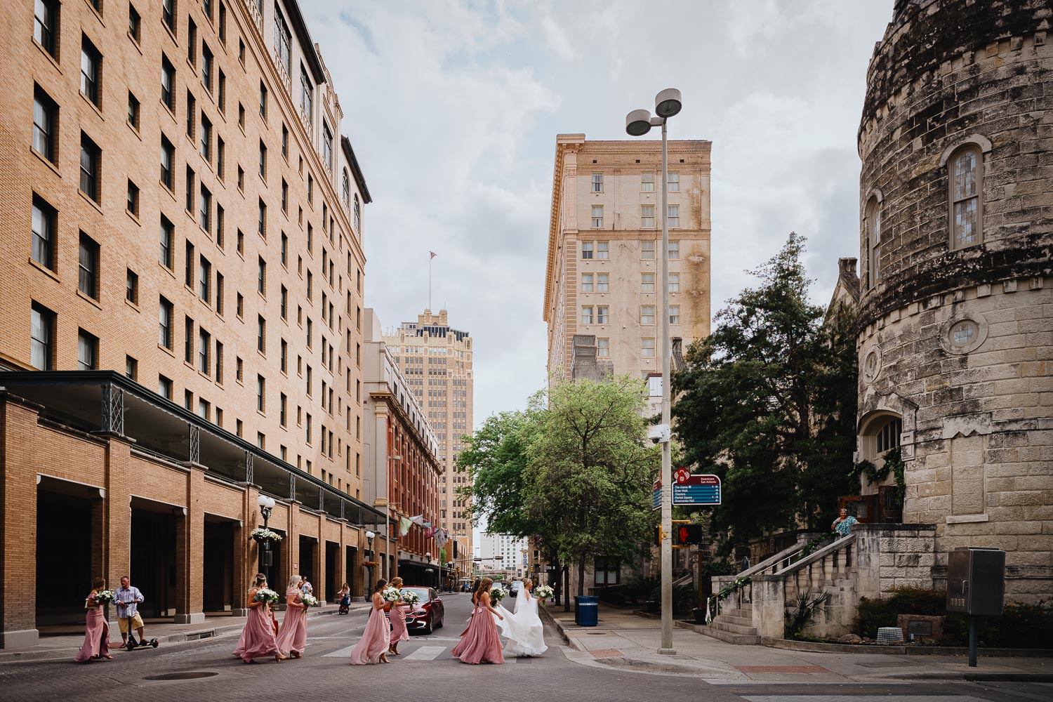 Bride and bridesmaids cross street from St Anthony Hotel San Antonio with skyline in background