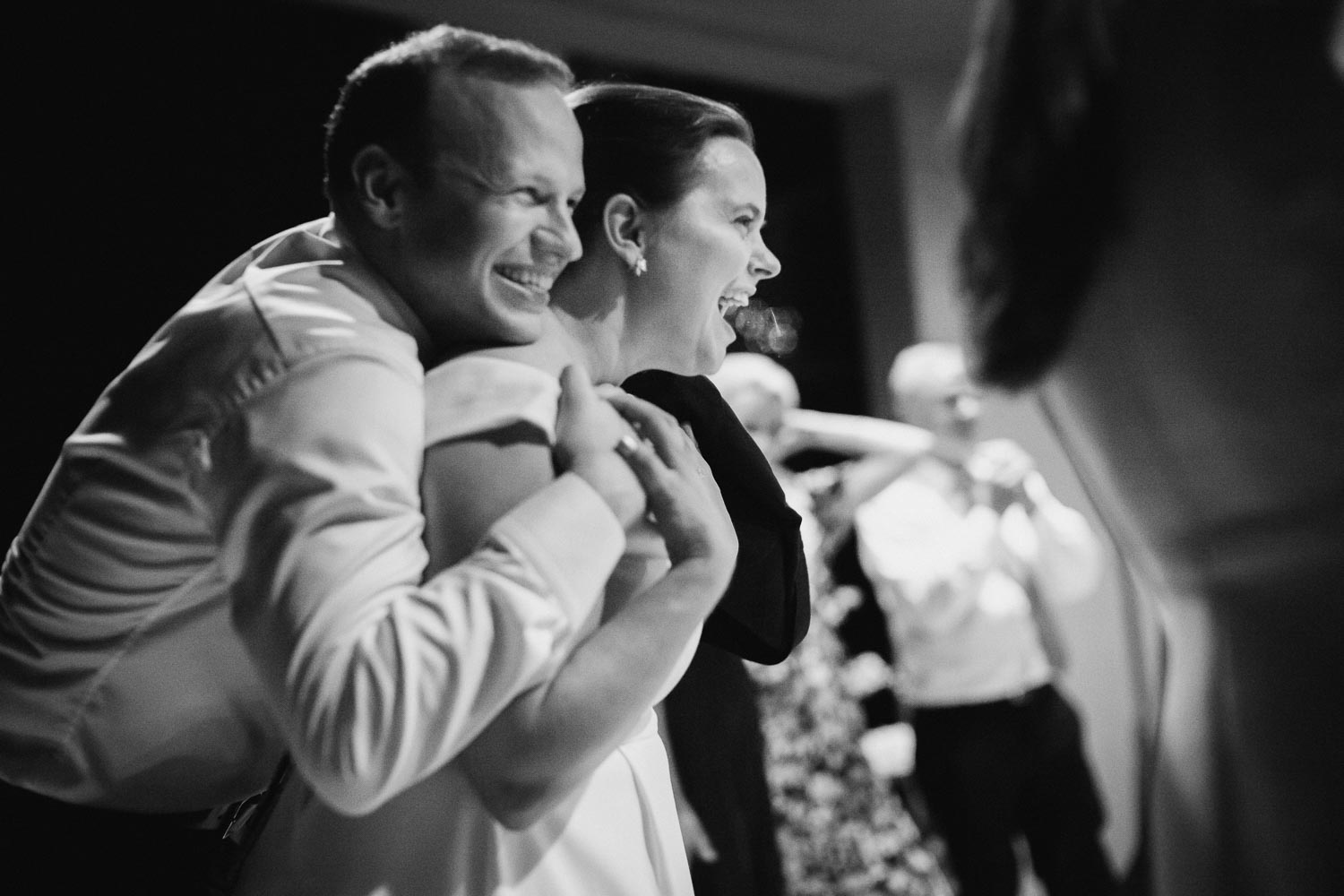 A newly minted couple hug in celebration during a wedding reception at a family home during the pandemic. 