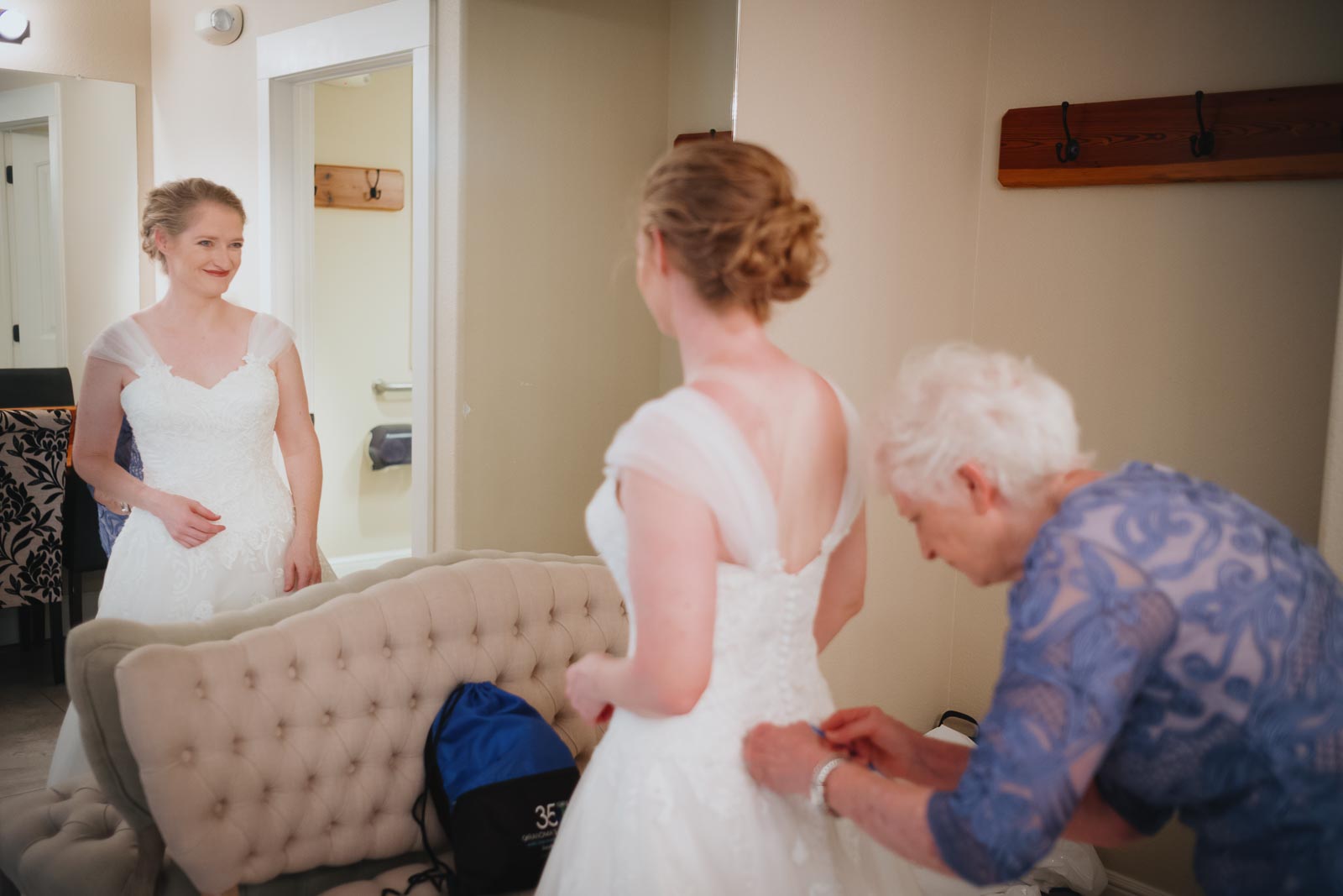 Mother of the bride buttons up the back of Maeve's dress at The Grande Ballroom moments before the wedding ceremony