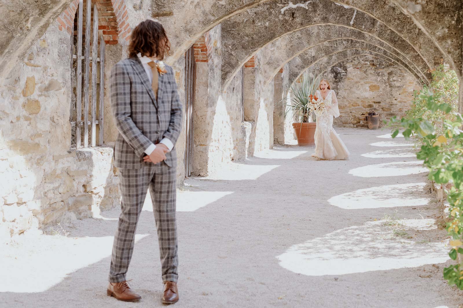 The groom turns his head toward a bride and their first look at San Jose Missions in San Antonio Texas