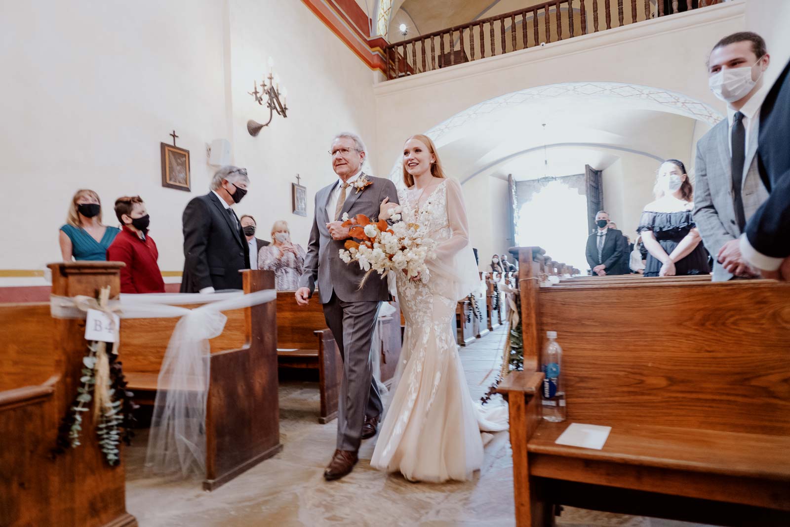 father and bride walk down the aisle at San Jose Missions Church Texas' largest colonial mission, with a carved limestone facade & rose window.