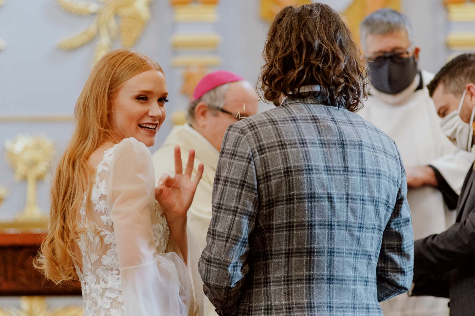 The bride gives an A OK sign to family and guests during a wedding ceremony