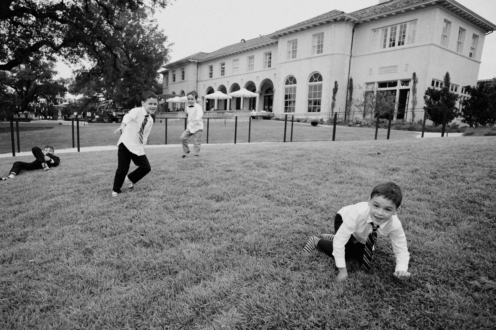 Boys playing shenanigans wedding reception on the slope of a lawn at at Commodore Perry Estate Austin Texa