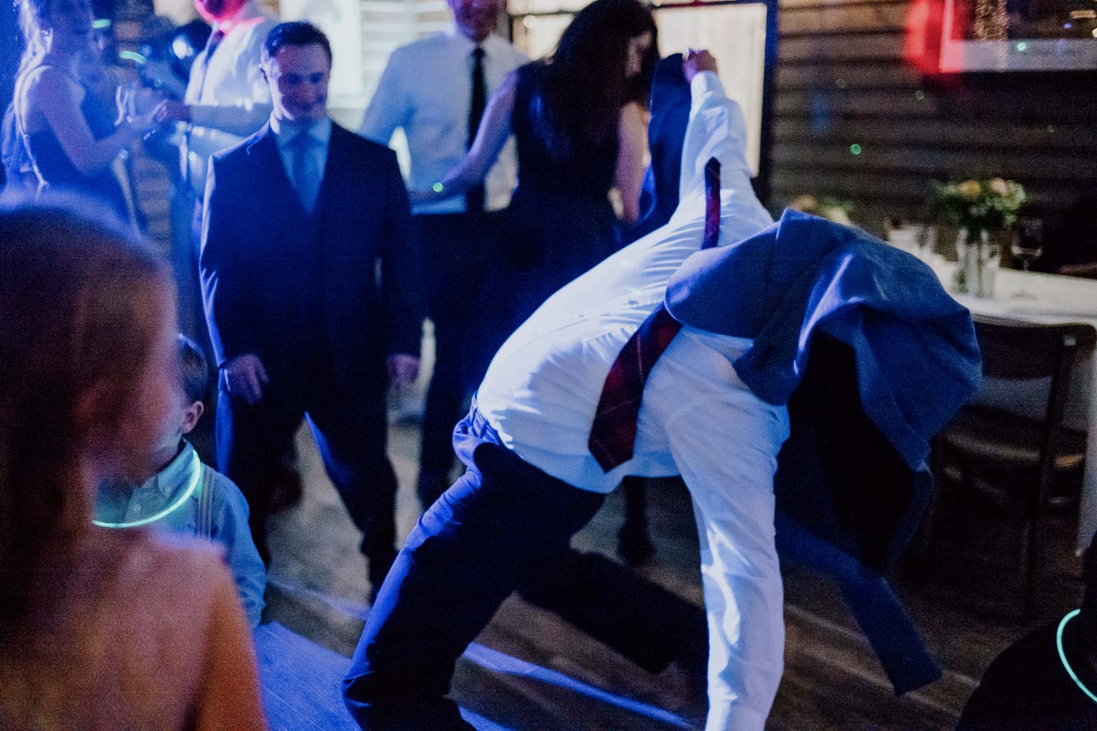 A guests bends back with his jacket over face at Ouisie's Table in Houston wedding reception