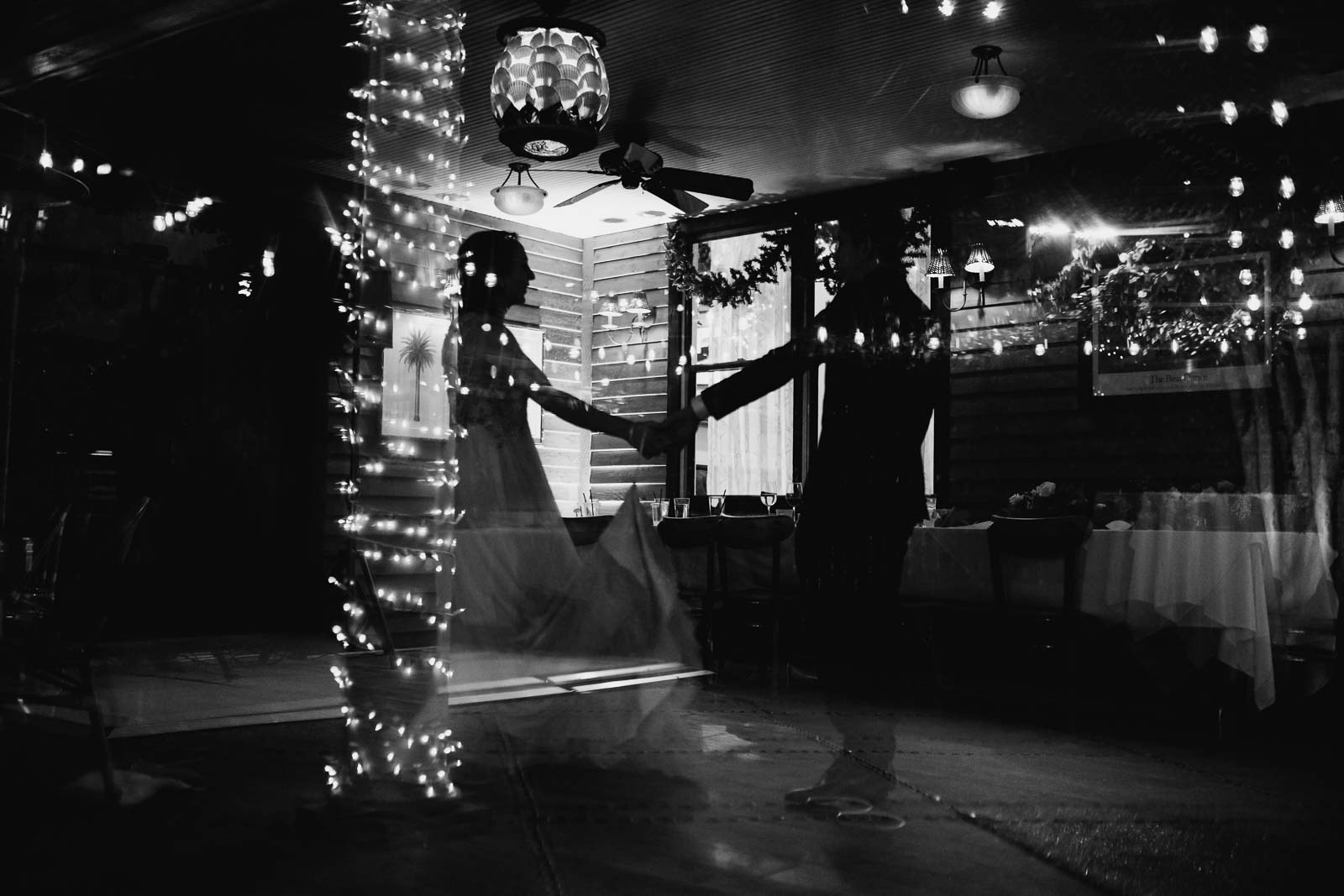 Last dance for newly wedded couple Martin and Katie shows couple silhouette holding hands with holiday lights glittering