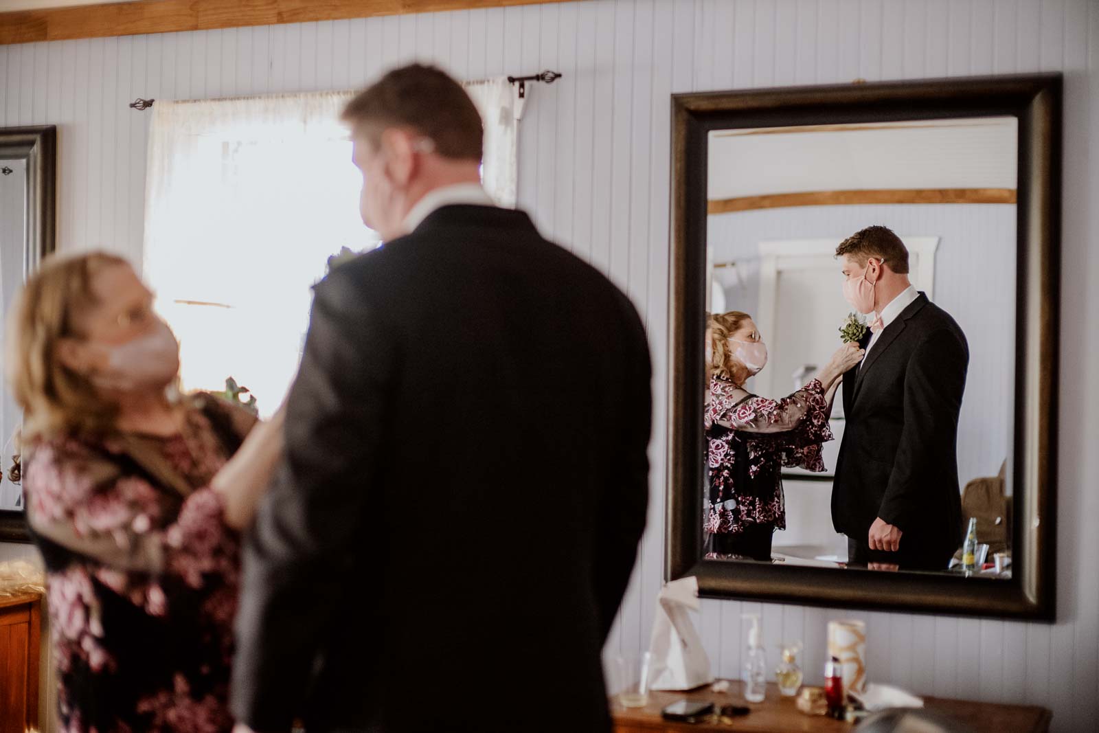 A mother adds a boutonnière  to her sons jacket pre-wedding