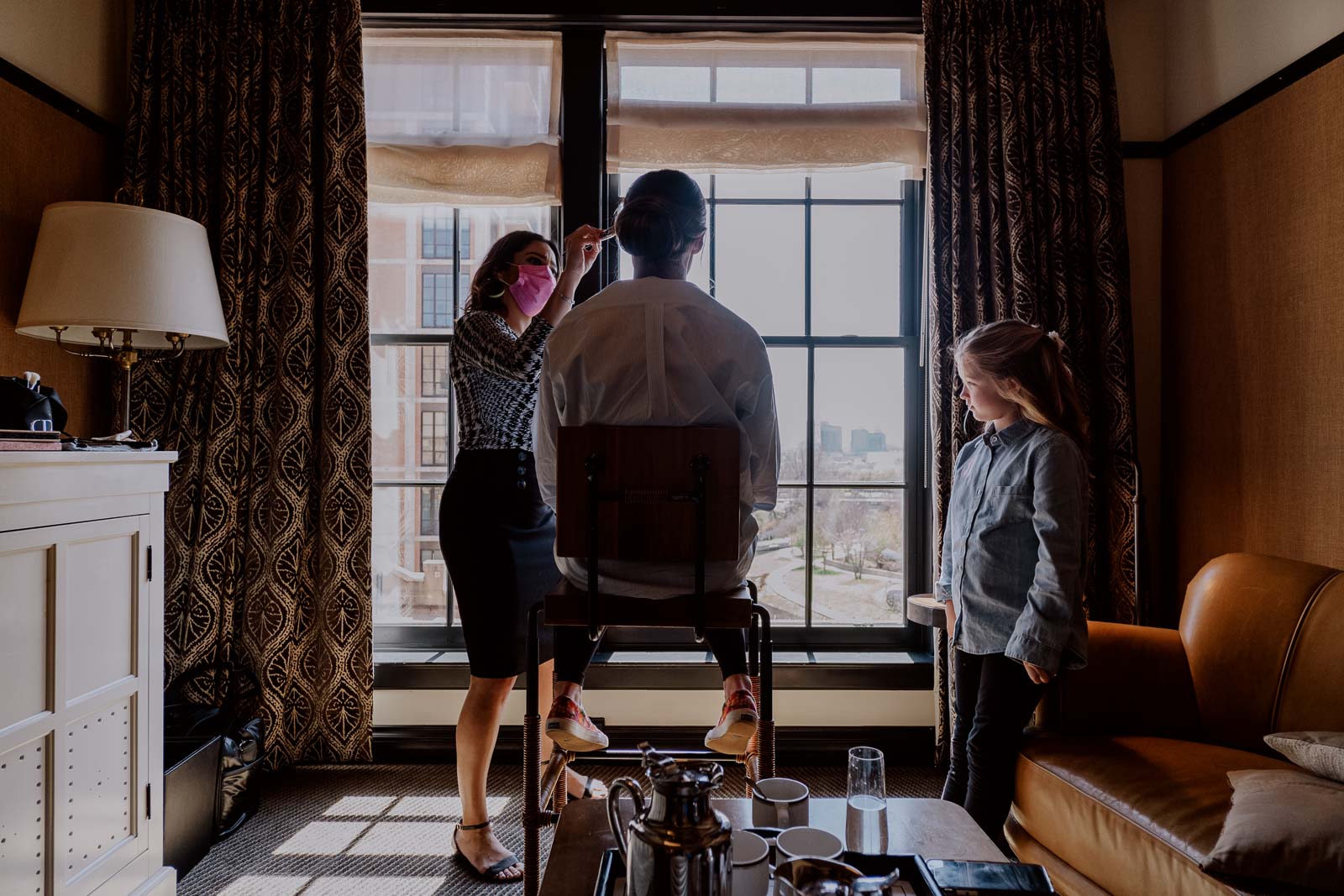 A Bride is silhouetted against the mirror at Hotel Emma has the hair and make up artist applies make up