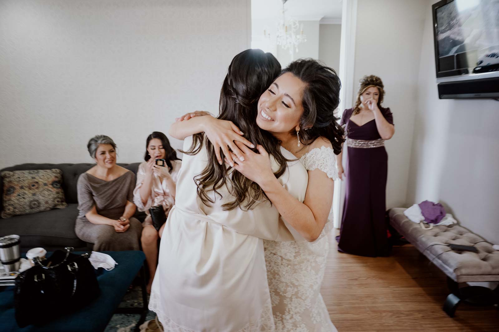 At Kendall point in Texas wedding venue the bride hugs her sister as her mother in law tears off in the background