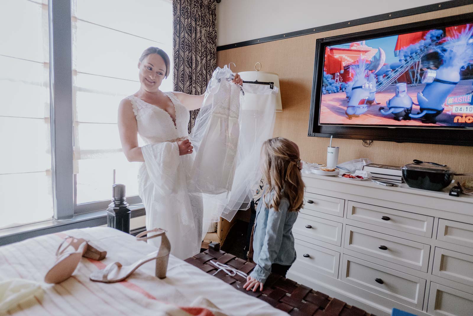 The bride in her dress compares the little flower girls dress to hers