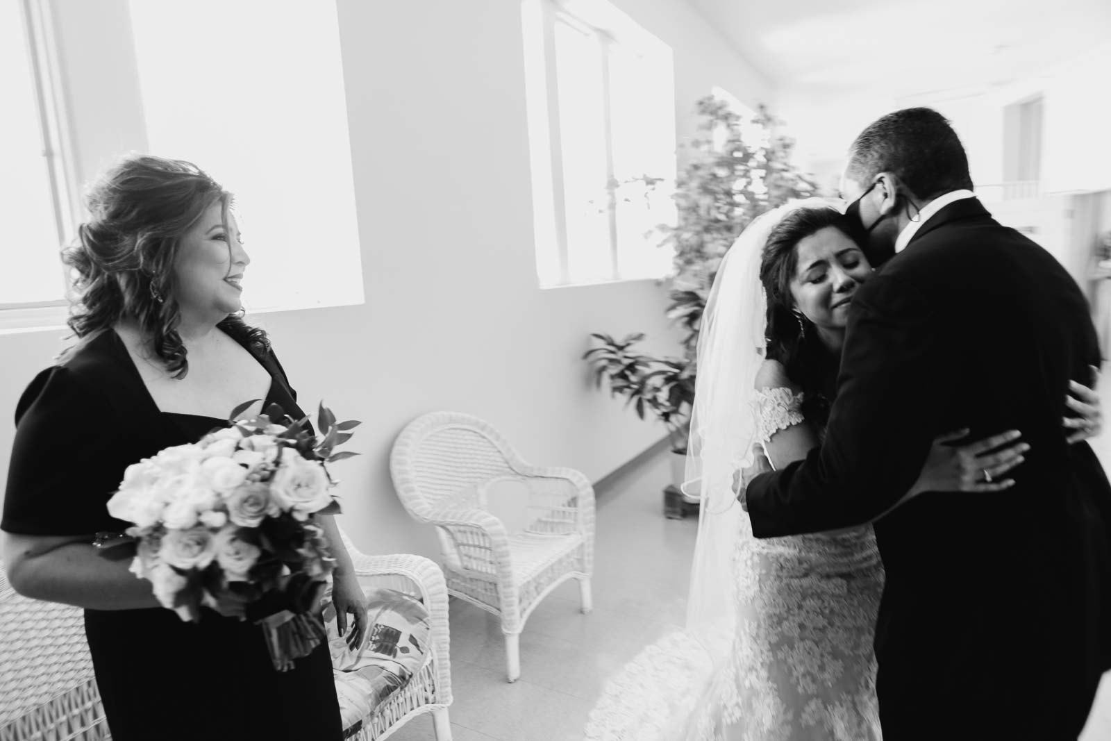 In an emotional moment the father of the bride hugs his daughter seeing her for the first time in her wedding dress as her mother cases adoringly in a documentary moment photograph photographed on a Leica M