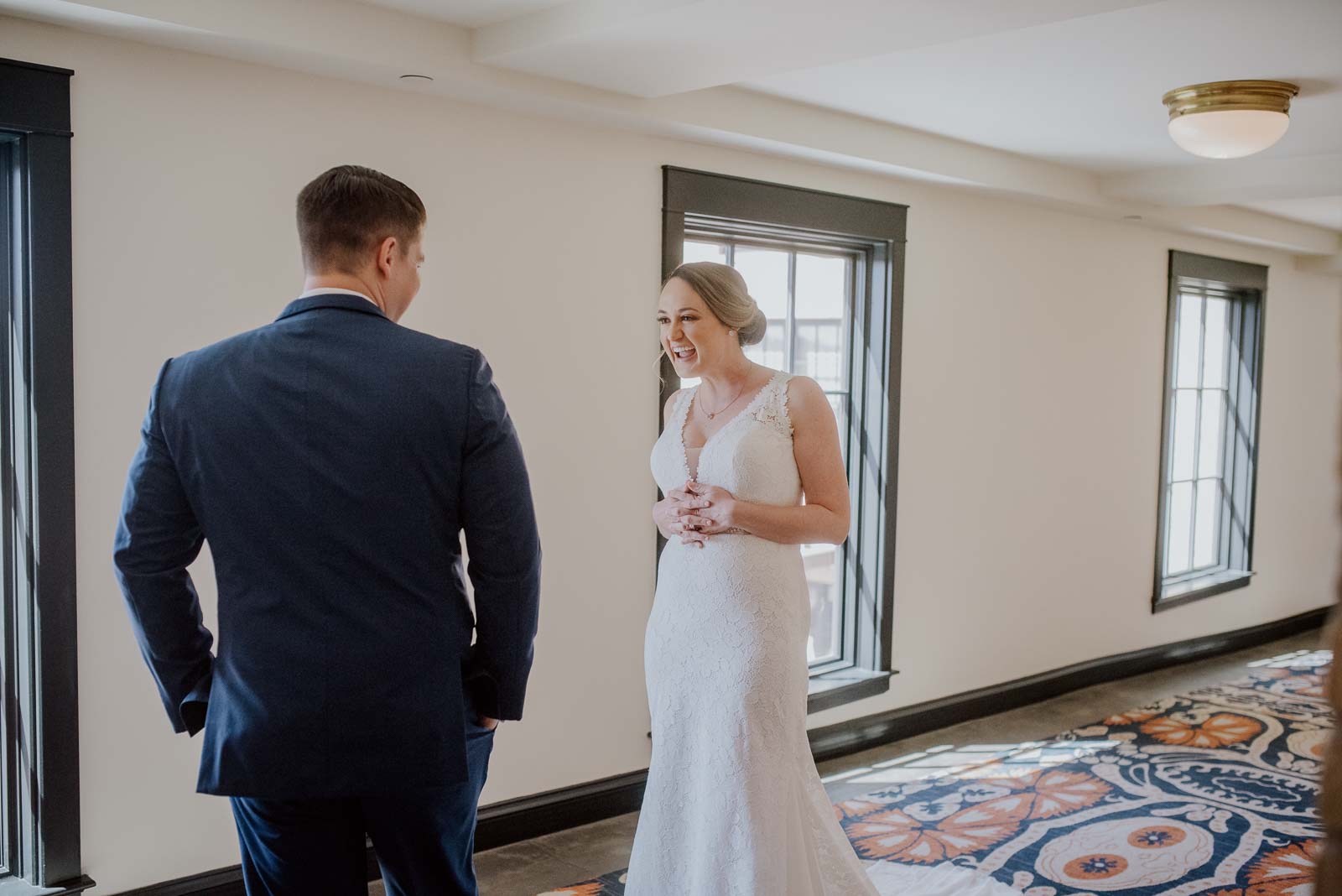 In a first look photograph talked away from prying eyes the groom turns to see his bride for the first time