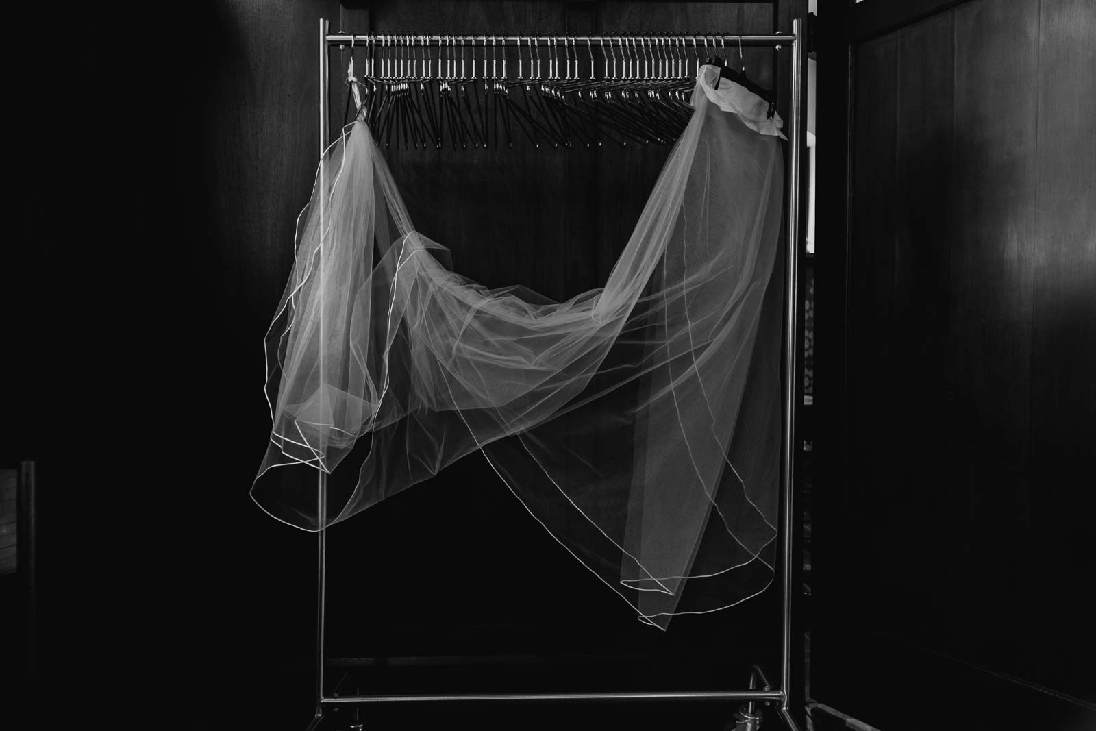A beautiful veil hangs in a candid caption in a black-and-white image hanging poetically