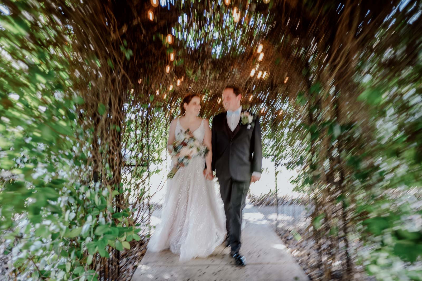 In a slow movement pan a couple walk towards the camera in a slow shutter speed at Spinellis wedding venue
