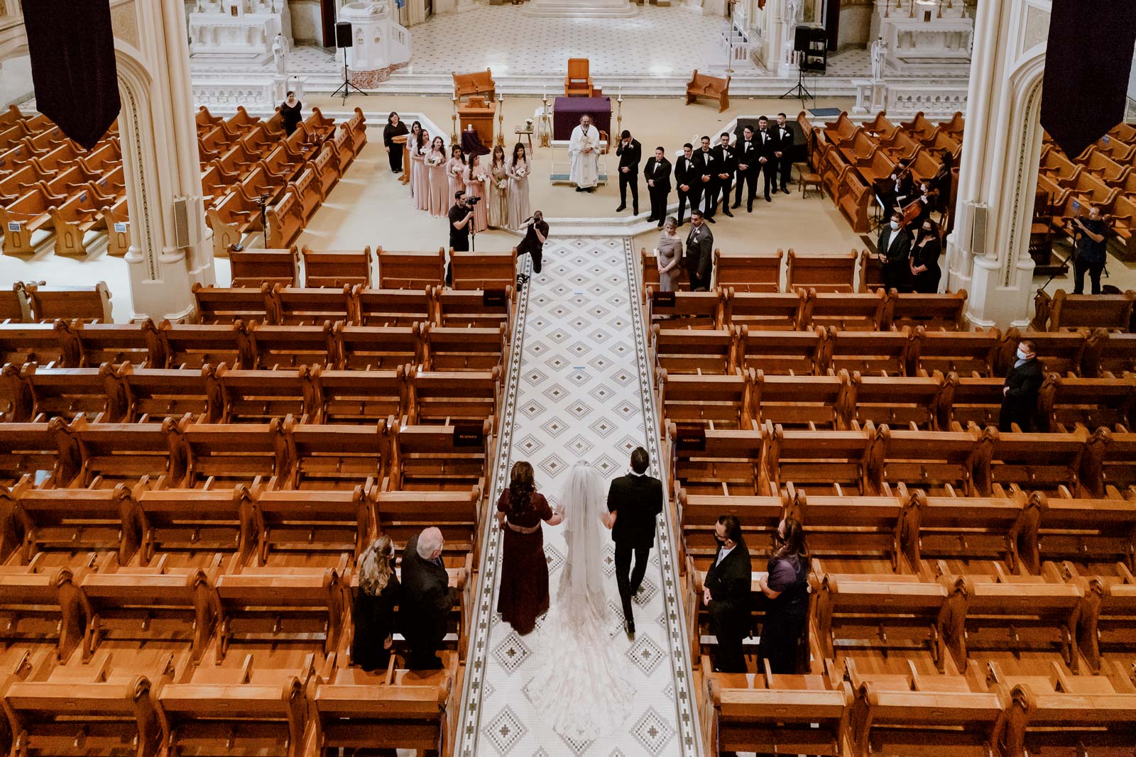 At sacred heart chapel in San Antonio a wedding ceremony commences with the bride S Escorted by the mother and father and the groom wipes away at here