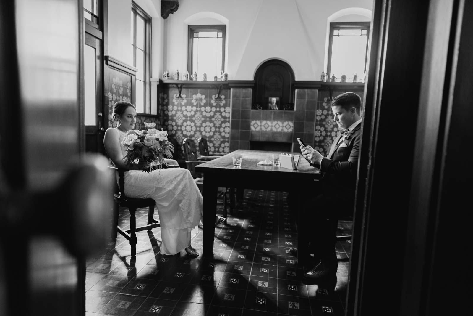 The bride and groom have a moment of peace before the ceremony in the tasting room as they sit in their chairs awaiting the moment