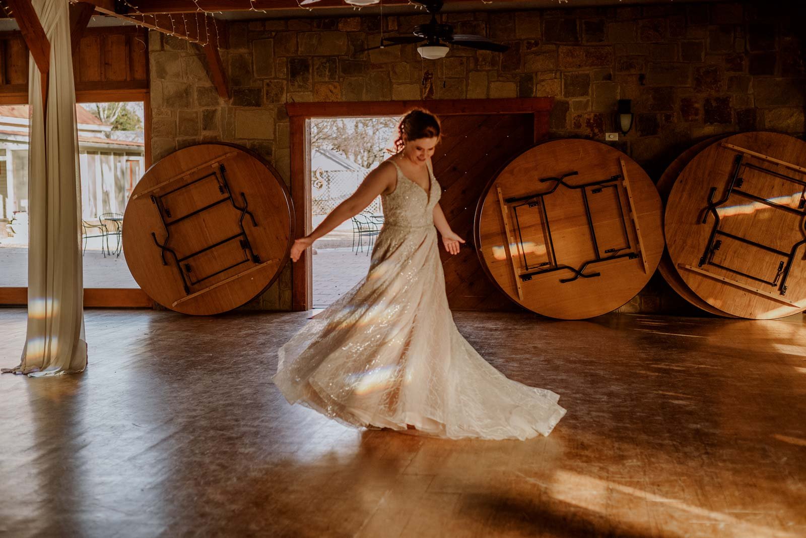 The bride twirls in the center of the frame at Spinellis wedding venue with tables operate in storage position