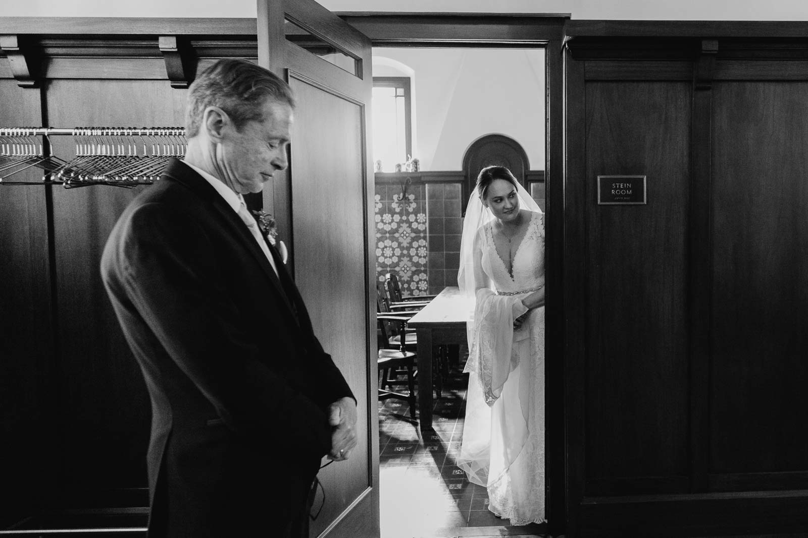 In a candid moment the bride peaks out looking toward the courtyard while the father of the bride had a moment of quiet clothes in his eyes